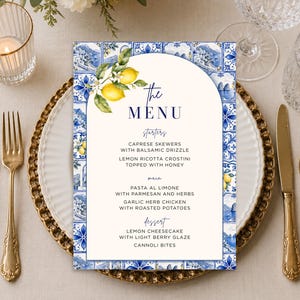Könnte beinhalten: Eine rechteckige Menükarte mit gewölbtem Oberteil, verziert mit einem blau-weißen Fliesenmuster-Rand und gelben Zitronenillustrationen. Der Text lautet: The Menu, Starters: Caprese Skewers, Lemon Ricotta Crostini, Main: Pasta al Limone, Garlic Herb Chicken, Dessert: Lemon Cheesecake, Cannoli Bites.