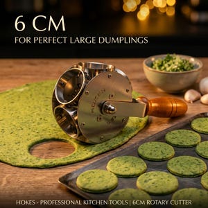 Pode incluir: Um cortador rotativo de aço inoxidável para raviólis, com 6 cm de diâmetro, com cabo de madeira. A imagem mostra o cortador sobre uma massa verde, com círculos recortados e raviólis preparados. O texto na imagem diz "6 CM FOR PERFECT LARGE DUMPLINGS".