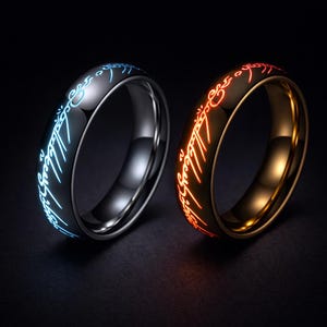 May include: Two rings with illuminated inscriptions. One ring is black with blue text, the other is gold with red text. The rings have a polished, metallic finish and are set against a dark backdrop. The rings are likely fantasy-themed jewellery.