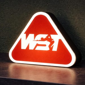 Könnte beinhalten: Ein rotes, dreieckiges Schild mit weißem Rand und den weißen Buchstaben "WST" sowie einer Silhouette einer Person beim Billardspielen. Das Schild ist beleuchtet und steht auf einer dunklen Oberfläche.