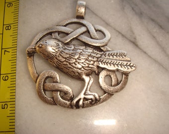 May include: Silver pendant featuring a detailed raven design with a Celtic knot border.