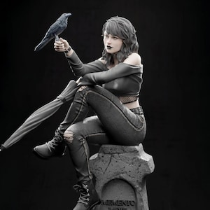 May include: A monochrome statue of a woman in black attire, holding a raven and an umbrella. She sits on a tombstone with the inscription "Memento Mori". The statue has a gothic theme and is set against a dark background.