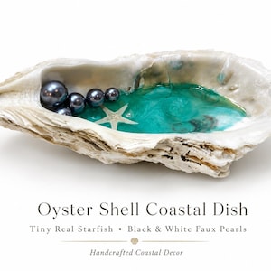 May include: An oyster shell dish featuring a glossy turquoise resin interior, a small white starfish, and several dark gray spherical beads. The text reads: Oyster Shell Coastal Dish, Tiny Real Starfish, Black & White Faux Pearls, Handcrafted Coastal Decor.