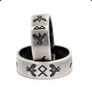 May include: Two silver rings with black etched designs. The top ring features a bird design, while the bottom ring features a bird and a symbol. The rings are stacked on top of each other. The text "HANDMADE TO ORDER WITH LOVE, JUST FOR YOU" is at the bottom of the image.