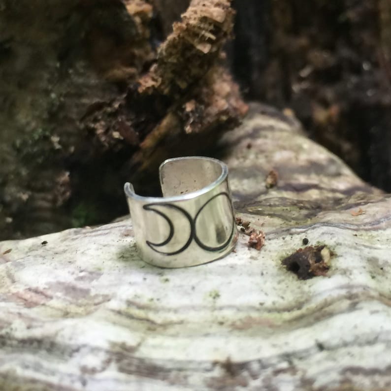 May include: Silver ear cuff with a triple moon design. The ear cuff is a simple band with a crescent moon design on the front.