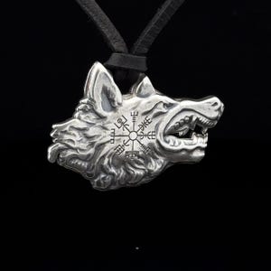 May include: Silver wolf head pendant necklace with a compass design featuring Norse runes. The pendant is on a black leather cord.