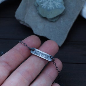 May include: A silver chain necklace with a rectangular pendant that says "MMXIX" in Roman numerals.
