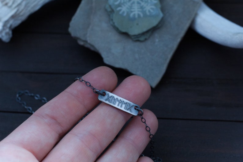 May include: A silver chain necklace with a rectangular pendant that says "MMXIX" in Roman numerals.