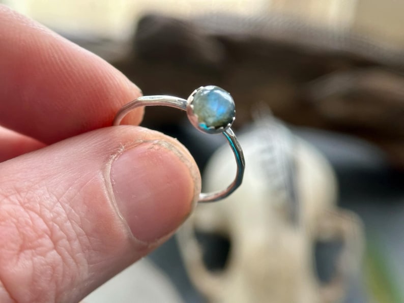 K&ouml;nnte beinhalten: Ein silberner Ring mit einem blaugr&uuml;nen Edelstein, der in einer Zargenfassung sitzt.