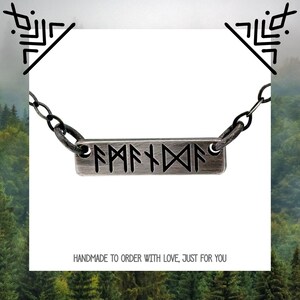 May include: A silver necklace with a rectangular pendant featuring the Norse runes for "family". The pendant is on a black cord chain.