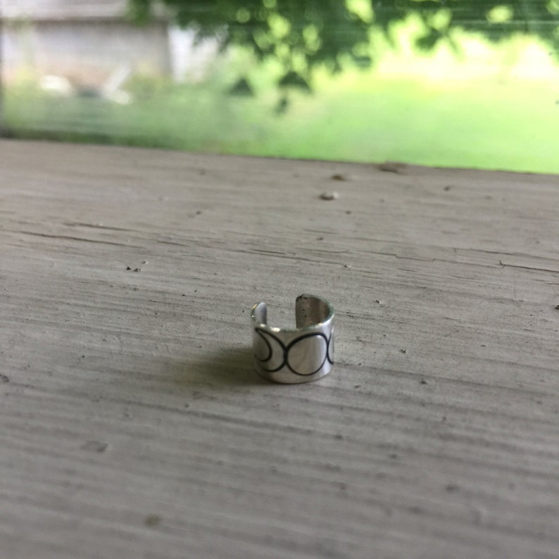 May include: Silver ear cuff with a triple moon design. The ear cuff is a simple, minimalist design with a silver finish.