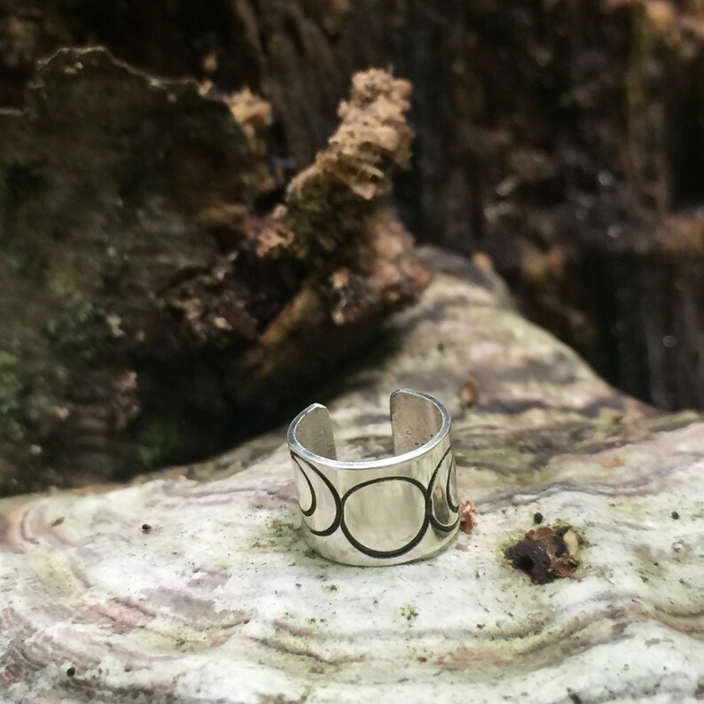 May include: Silver ear cuff with a triple moon design. The cuff is open and has a smooth, polished finish.