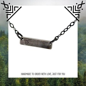 May include: A silver necklace with a rectangular tag that reads "Wicked Griffin 999FS". The necklace has a black chain.