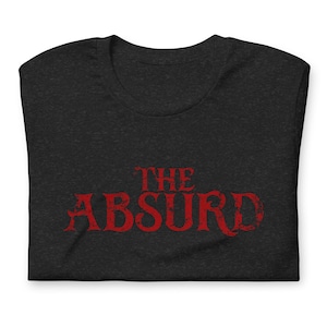 May include: Dark heather gray t-shirt with the red text "THE ABSURD" in a distressed font. The shirt is folded, showcasing the design prominently. A casual, unisex tee.