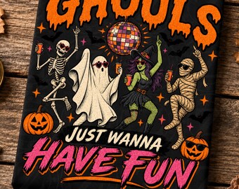 May include: A black t-shirt featuring a graphic of a skeleton, a ghost, a witch, and a mummy dancing under a disco ball. The text reads GHOULS JUST WANNA HAVE FUN in orange and pink. Orange pumpkins and small stars are scattered throughout.
