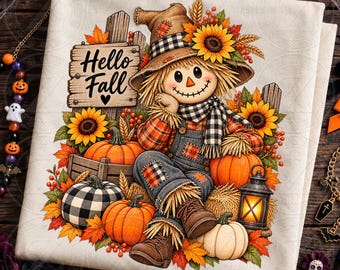May include: A cream-colored fabric featuring a graphic of a scarecrow wearing a plaid shirt, denim overalls, and a hat. The design includes sunflowers, pumpkins, a lantern, and a wooden sign with the text Hello Fall with a heart.