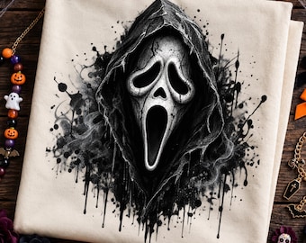 May include: A cream-colored fabric item featuring a central graphic of a white, cracked, elongated mask with hollow eyes and an open mouth, framed by a dark, hooded cloak with black ink-like splatters and drips extending outward from the center.