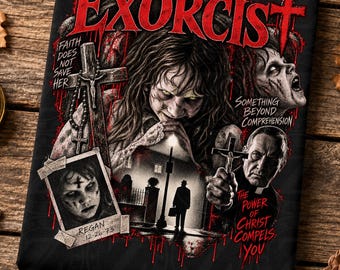 May include: A black graphic t-shirt featuring The Exorcist movie artwork. The design includes a central possessed figure, a priest holding a crucifix, a street scene, and a photo of Regan with the text Faith Does Not Save Her, Something Beyond Comprehension, and The Power of Christ Compels You.