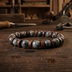 May include: A beaded bracelet featuring gray stone beads and wooden spacers. The bracelet is displayed on a wooden surface, showcasing the natural tones of the materials. The bracelet's design is simple and elegant, suitable for everyday wear.