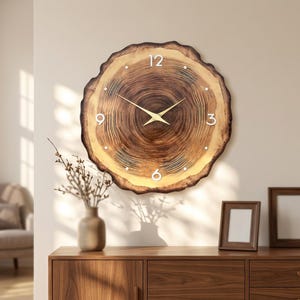 May include: A round wall clock crafted from a natural wood slice featuring visible dark brown tree rings, a light-colored outer edge, white numerals at the 12, 3, 6, and 9 positions, and thin gold-toned metal hour and minute hands.