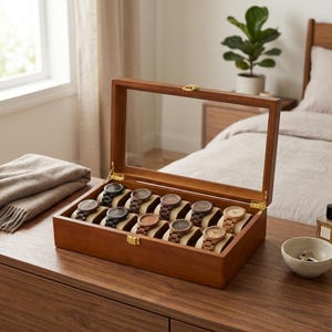 May include: A wooden watch display case with a glass lid, showcasing twelve wristwatches with various band and face colors. The case is open, revealing the watches resting on cream-colored cushions. The case is on a wooden surface.
