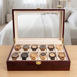 May include: A wooden watch display case with a glass top, showcasing twelve wooden watches. The case is a dark brown with a gold clasp. The watches have various wood tones and face designs, offering a range of styles.