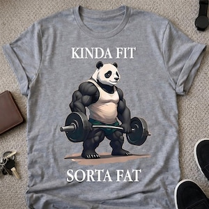 May include: Gray t-shirt with a cartoon panda lifting weights. The panda is muscular and wearing a tank top and shorts. The text "KINDA FIT" is above the panda, and "SORTA FAT" is below.