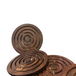 May include: A set of wooden maze puzzles. Each puzzle is a circular disc with concentric grooves forming a maze. The wood has a warm, brown tone. A small metal ball is visible in one of the mazes.