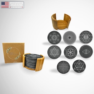 May include: A set of round dark gray stone coasters featuring white geometric line art designs. The set includes a light brown bamboo holder and a square cardboard box with a circular logo and leaf illustrations. The coasters are stacked in the holder.