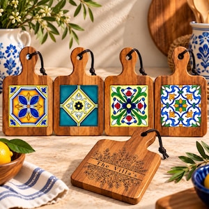 May include: Five wooden serving boards with handles and black leather cords. Four boards feature square ceramic tiles with colorful floral and geometric patterns. One board is engraved with a floral design and the text The Villa's.