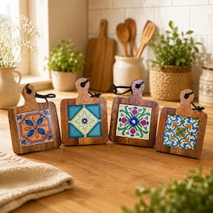 May include: Four decorative wooden chopping boards with patterned ceramic tiles. Each board has a handle with a black string for hanging. The tiles feature floral and geometric designs in blue, yellow, and red.