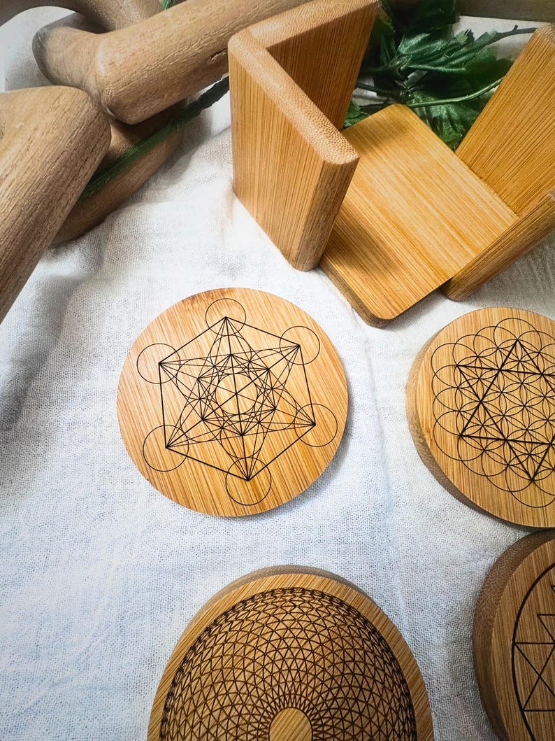 May include: A collection of bamboo coasters with geometric designs. The coasters feature intricate patterns, including the Metatron's Cube and other sacred geometry symbols. A bamboo holder and other bamboo items are also visible.