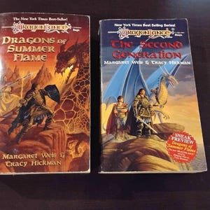 以下が含まれることがあります： ドラゴンランスシリーズの2冊のペーパーバック。最初の本「Dragons of Summer Flame」は、戦士とドラゴンのイラストが特徴です。2冊目の「The Second Generation」は、剣を持った女性とドラゴンが描かれています。