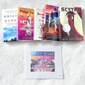 May include: A collection of hardcover books with colorful covers, including "Night Road," "Seven Summers," and "Scythe." Below the books is a small, square, cross-stitched piece with the titles of the books.
