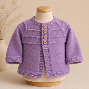 May include: A light purple long-sleeve knit cardigan featuring a round neckline, garter stitch trim on the cuffs and hem, and four small wooden buttons shaped like flowers down the front placket. The garment is displayed on a mannequin torso.