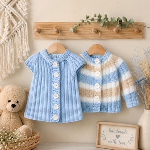 Può includere: Due cardigan in maglia appesi a grucce di legno. Il cardigan a sinistra è azzurro tinta unita con una trama a coste e bottoni bianchi a forma di fiore. Il cardigan a destra presenta righe orizzontali azzurre, beige e bianche con bottoni tondi.