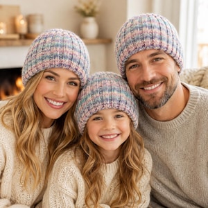 Può includere: Tre berretti in maglia a coste abbinati in una tavolozza di colori pastello variegati con tonalità tenui di rosa, blu e crema. Ogni berretto presenta una struttura in maglia spessa e testurizzata con un bordo ripiegato per calore e copertura.
