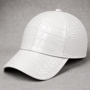 Può includere: Un cappellino da baseball bianco caratterizzato da una texture in rilievo che imita la pelle di coccodrillo. Il design presenta una corona strutturata a sei pannelli con un bottone coordinato sulla sommità e una visiera curva con scaglie.