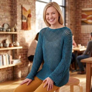 以下が含まれることがあります： 長袖とボートネックの、ティールブルーのオープンニットセーター。セーターはわずかにフレアした裾です。マスタード色のパンツを履いた人が木製のスツールに座っています。背景にはレンガの壁と木製の棚があります。