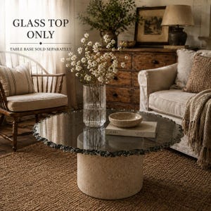 Puede incluir: Un tablero de mesa circular de cristal con un borde texturizado e irregular que descansa sobre una base cilíndrica de piedra beige. El texto GLASS TOP ONLY y TABLE BASE SOLD SEPARATELY es visible. La superficie de cristal es transparente.