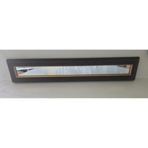 May include: A long, rectangular mirror with a dark brown frame and a gold inner trim. The mirror is mounted on a white surface. The frame has a beveled edge, adding a touch of elegance to the design. The mirror reflects the surrounding environment.
