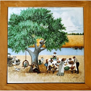 May include: A framed ceramic tile featuring a pastoral scene. A large tree dominates the center, with people picnicking and playing nearby. A vintage car and a dog are also present. The artwork is set in a field with a river and geese in the background.