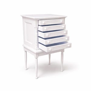 Op de afbeelding: Een witte kleine ladekast met zes laden, waarvan één gedeeltelijk open. De kast staat op vier slanke poten en heeft decoratieve lijsten en ladeknopen. De laden zijn leeg, met een lichtblauwe binnenkant.