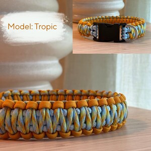 Peut inclure: Un collier tress&eacute; pour chien, mod&egrave;le "Tropic", avec un motif de couleurs jaune, bleu et orange. Le collier est &eacute;quip&eacute; d'une boucle en plastique noir et d'un anneau m&eacute;tallique argent&eacute;. Le texte "Model: Tropic" est visible.
