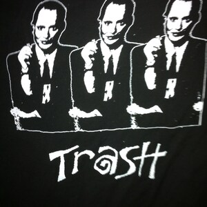 May include: Black and white graphic print of three men wearing suits and ties. The word "Trash" is printed below the men.