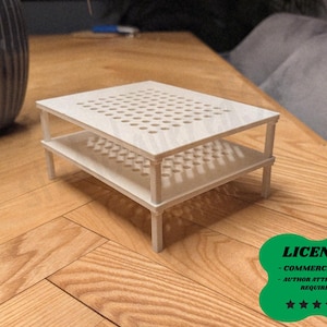 May include: A small, two-tiered wooden table with a light finish. The top tier features a grid of evenly spaced holes. The table is supported by four legs and sits on a wooden surface. The table is approximately 12 inches long and 8 inches wide.