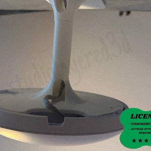 May include: A white and gray lamp base with a curved stem and a circular light. The base has a built-in light and a power cord. The image also includes a green license badge.
