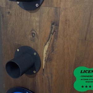 May include: Close-up of a wooden surface with black metal fixtures attached. The wood has a natural grain and a light-coloured streak. The fixtures appear to be part of a larger structure. A green license badge is in the bottom right corner.