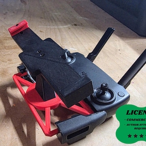 May include: A black and red drone controller mount. The mount is designed to hold a drone controller and is made of plastic. The mount has a red base and a black top. The controller has two antennas and several buttons.