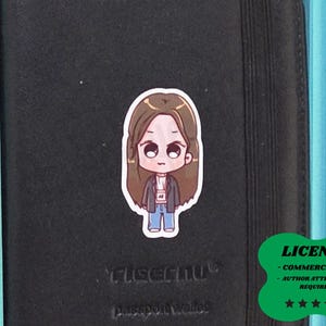 May include: A sticker of a cartoon character with brown hair, wearing a jacket, shirt, and jeans. The sticker is on a black passport wallet. A green sticker with the text "LICENSE - COMMERCIAL USE - AUTHOR ATTRIBUTION REQUIRED" is in the bottom right corner.